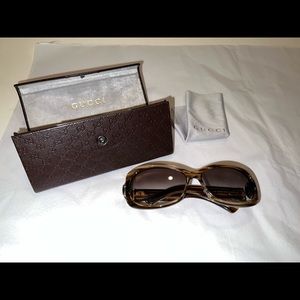 Gucci sunglasses with brown acetate frame adorned with gold buckle logo side.